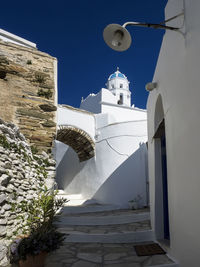 Low angle view of cross amidst buildings against sky