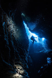 Sunlight falling on silhouette person scuba diving undersea