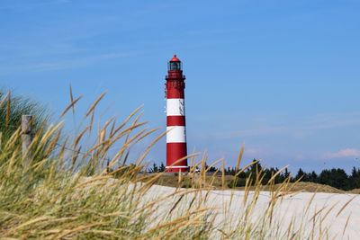 Lighthouse on beach against sky