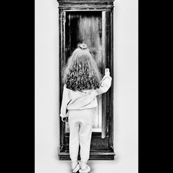 Rear view of woman standing against door