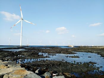 Wind turbines on land against sky