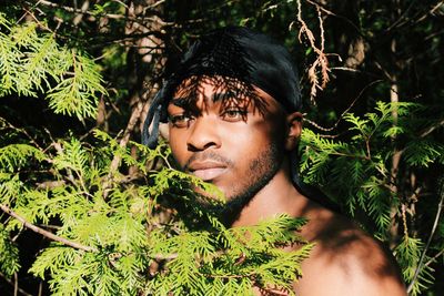 Close-up of thoughtful man standing amidst branches