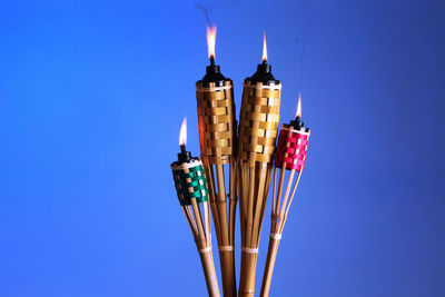 Close-up of illuminated tiki torches against blue background