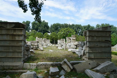 Stack of stone wall by trees on field against sky