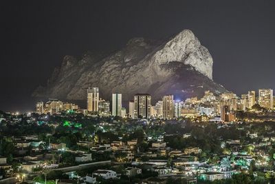 High angle view of illuminated cityscape against mountains at night