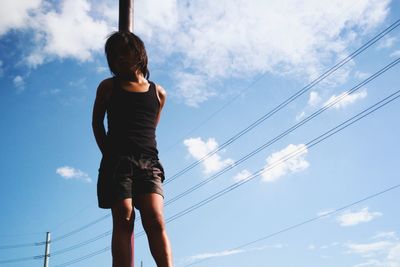 Low angle view of girl standing against sky