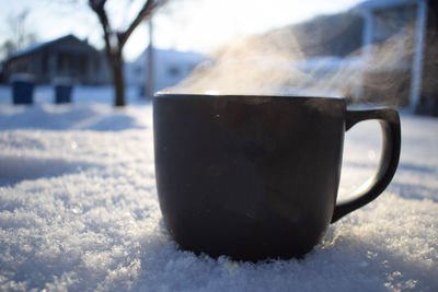 Close-up of coffee cup on snow covered table