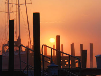 Silhouette railing by sea against sky during sunset