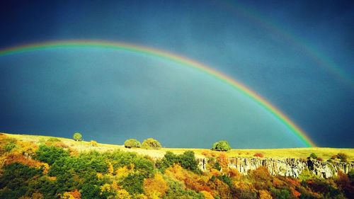 Scenic view of rainbow over mountain against sky