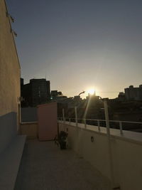 Street by buildings against sky during sunset