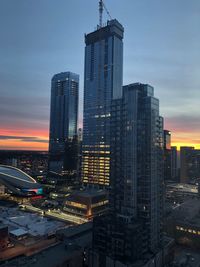 Modern buildings in city against sky at dusk