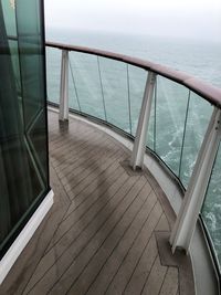 Wooden railing by sea against sky