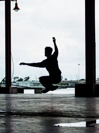 Man with arms raised against sky