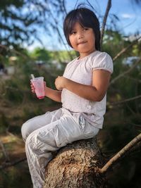 Portrait of young girl eating ice cream while sitting on a log.