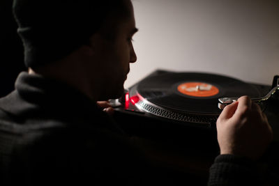 Rear view of man playing turntable
