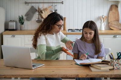 Female friends using laptop at home