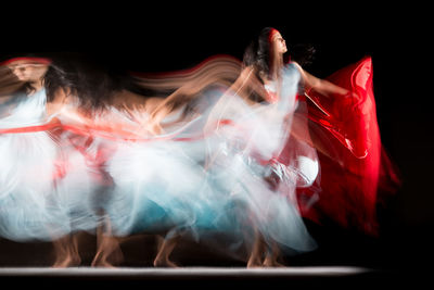 Blurred motion of people dancing against black background
