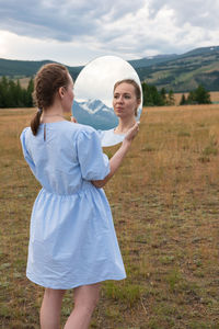 Happy woman standing on field against sky