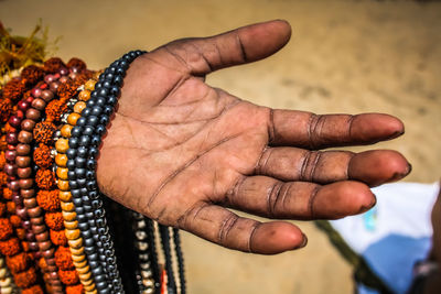 Cropped hand of man selling bead necklaces at beach