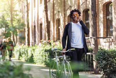 Smiling man walking with bicycle on street