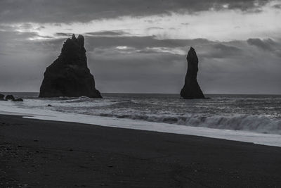 Rock formation on beach against sky