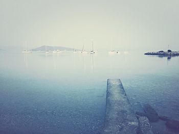 Sailboats moored in sea against clear sky