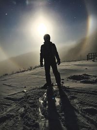 Silhouette of snowboarder on field against sky during winter