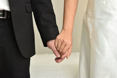 Midsection of bride and bridegroom holding hands