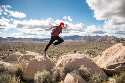 Energetic teen jumping across rock in joshua tree national park