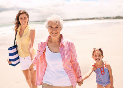 Happy grandmother with family walking on beach