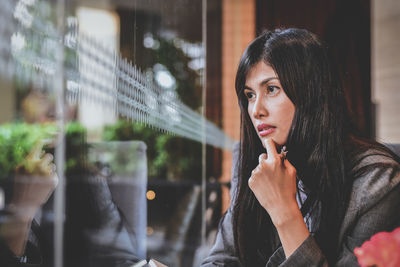 Thoughtful woman looking through window