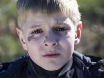 Close-up portrait of boy with soot smear on face during sunny day