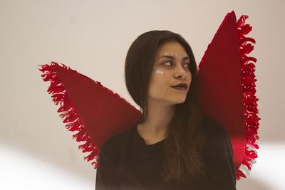 Close-up of young woman wearing angel costume against wall