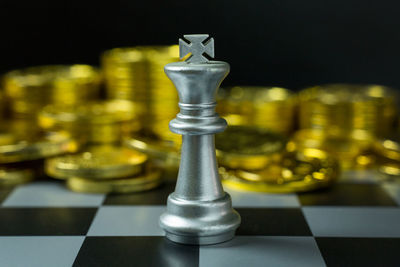 Close-up of chess piece and coins on board