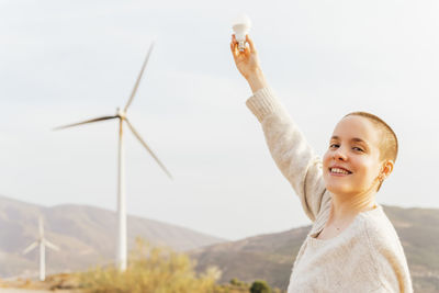 Portrait of smiling boy with arms raised against sky