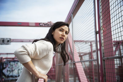 Side view of young woman looking away while standing on williamsburg bridge