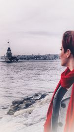 Woman standing by sea against sky during winter