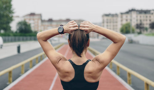 Midsection of woman with arms raised standing in city