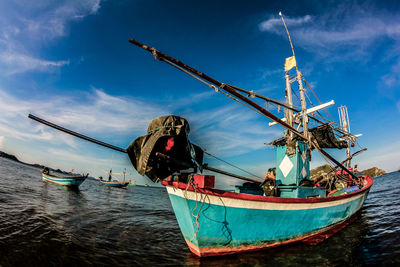 Fishing boats moored in sea against sky
