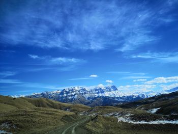 Scenic view of snowcapped mountains against blue sky