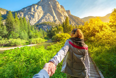 Rear view of woman with umbrella on mountain against sky