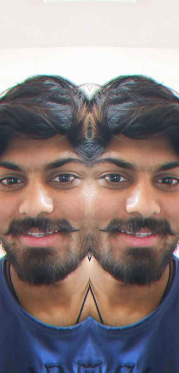 portrait, human hair, beard, facial hair, looking at camera, hairstyle, headshot, men, adult, young adult, front view, moustache, human face, indoors, close-up, human head, person, smiling, lifestyles, nose, emotion, one person, stubble, clothing, black hair