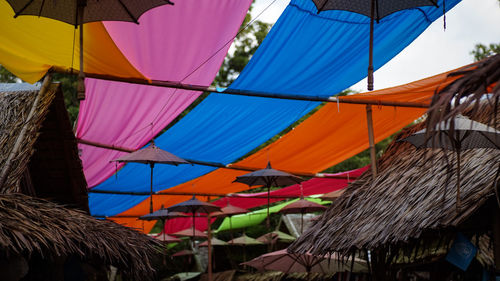 Multi colored umbrellas hanging on roof of building