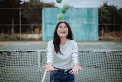 Young woman playing with balls at tennis court