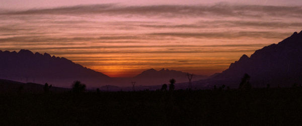 Scenic view of silhouette mountains against orange sky