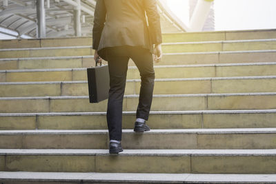 Low section of a business man walking on staircase