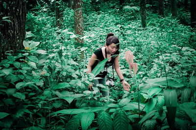 Young woman standing amidst plants at forest