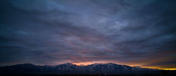 Scenic view of snow covered mountains against cloudy sky at sunrise