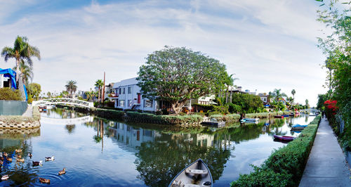 Boats in canal amidst buildings in city against sky