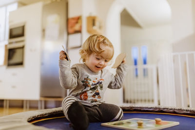 Smiling cute baby girl playing while sitting at home